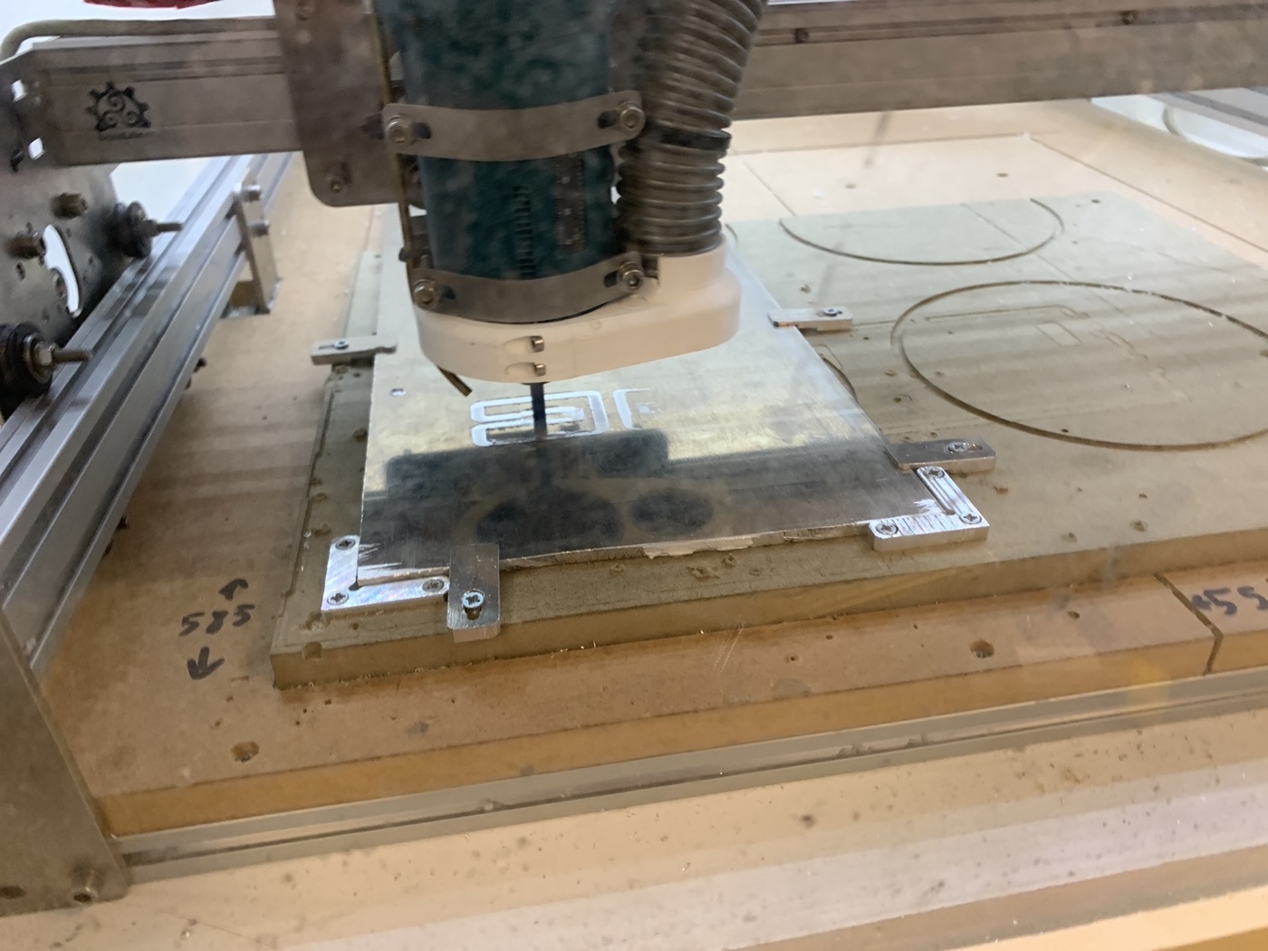 La fresadora eShapeoko con un cabezal Makita cortando una chapa de aluminio sujeta a la mesa con bridas